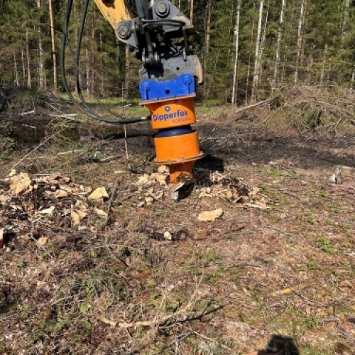 Dipperfox rodfræser monteret på gravemaskine under stubfræsning og fjernelse af trærødder i skovområde.