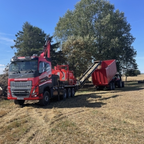 Flishugger monteret på lastbil producerer flis og fylder container ved professionel flishugning.