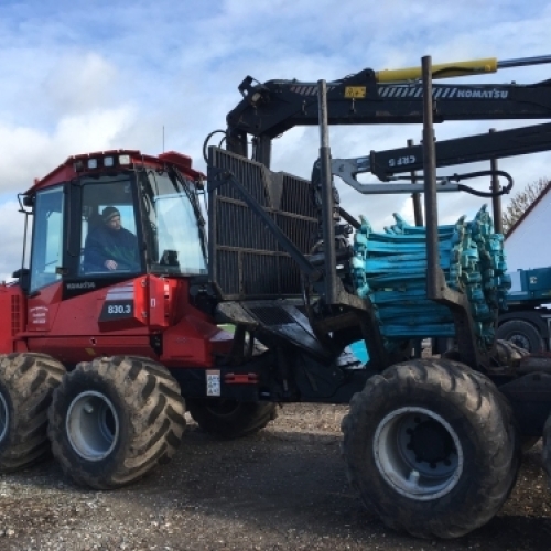 Skovmaskine læsser tømmer under maskinskovning og professionel skovdrift.